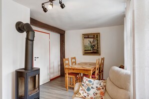 Una habitación con una estufa de leña, una mesa de comedor con sillas, un sofá y un cuadro en la pared.