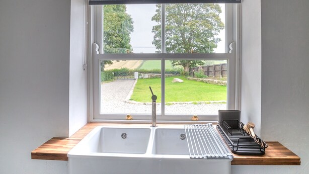 Een keuken met een raam, een spoelbak en een afdruiprek.