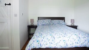 Een slaapkamer met een bed, twee nachtkastjes en een deur.
