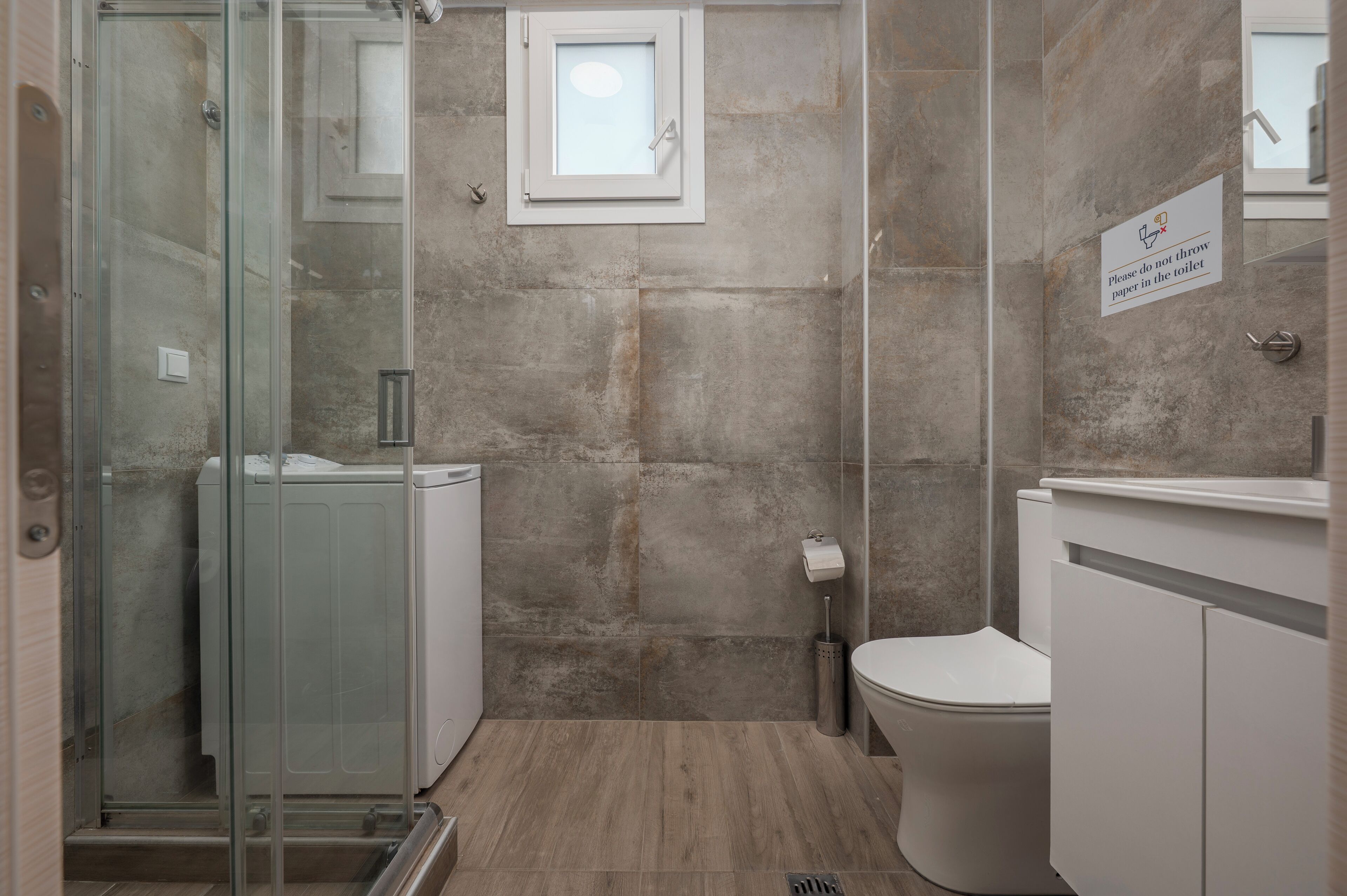 Un baño con cabina de ducha de vidrio, inodoro y lavamanos.