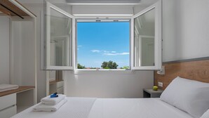 Ein Hotelzimmer mit Bett, Nachttisch, Fenster und freiem Blick, sowie einem Holz-Kopfteil.