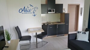 Een knus verblijf met een kitchenette, een eethoek en een bank.