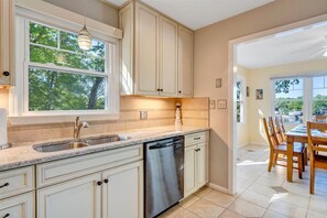 Una cocina equipada con lavavajillas, pileta doble y comedor con mesa y sillas.