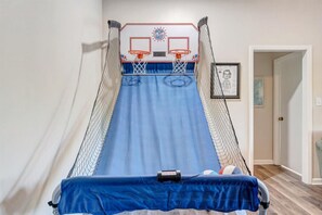 A room with a blue slide, a basketball hoop, and a door leading to another room.