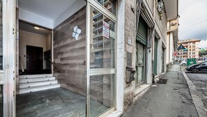 A building with a glass entrance, a staircase leading inside, and a street view with parked cars. - [New Modern Apt.] Center 10 min • Hyper WiFi • A/C (Genoa)