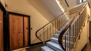 A staircase with marble steps and wooden railings, a wooden door, and a doormat. - [New Modern Apt.] Center 10 min • Hyper WiFi • A/C (Genoa)