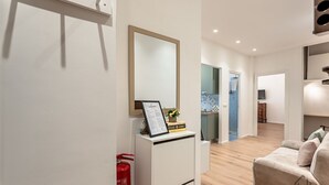 A modern living room with a sofa, a white cabinet with a mirror, and a small table with a framed certificate. - [New Modern Apt.] Center 10 min • Hyper WiFi • A/C (Genoa)