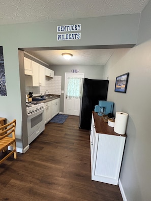 A kitchen with white cabinets, a black refrigerator, and a sign reading 'KENTUCKY WILDCATS'.
