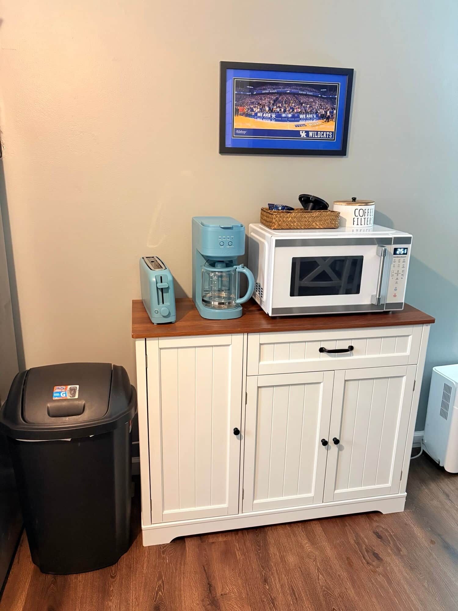 Eine Küchenzeile mit Kaffeemaschine, Toaster, Mikrowelle und Mülleimer.