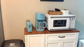 Eine Küchenzeile mit Kaffeemaschine, Toaster, Mikrowelle und Mülleimer.