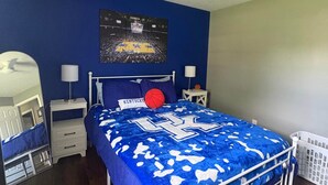 Une chambre à coucher avec un lit, un ventilateur de plafond, une affiche de basket-ball et un berceau.