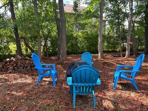 Three blue chairs arranged in a semi-circle facing a pile of logs and a building in the background. - Ruppside Retreat I Cozy 2BR I 15m to RRG I Wi-Fi (Stanton)