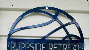 Un panneau circulaire portant l’inscription « RUPPSIDE RETREAT » est fixé sur un mur blanc.