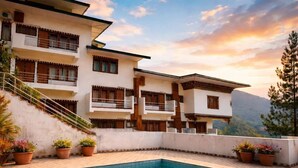 Un edificio de varios pisos con balcones, piscina y plantas en macetas.