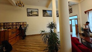 Un vestíbulo de hotel con suelo de madera, mostrador de recepción y una columna grande.