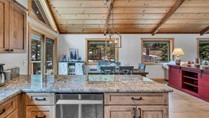 A kitchen with wooden cabinets, granite countertops, and a hanging light fixture. - Tahoe City Escape | Beach Access + Large Deck (Tahoe City)