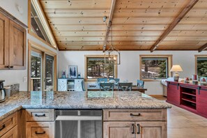 A kitchen with wooden cabinets, granite countertops, and a hanging light fixture. - Tahoe City Escape | Beach Access + Large Deck (Tahoe City)