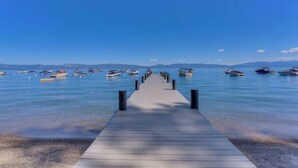 A wooden pier leading to a calm lake with boats. - Tahoe City Escape | Beach Access + Large Deck (Tahoe City)