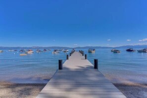 A wooden pier leading to a calm lake with boats. - Tahoe City Escape | Beach Access + Large Deck (Tahoe City)