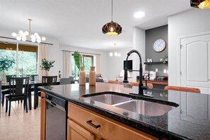 Eine moderne Küche mit einer zentralen Kochinsel, einem Essbereich mit Stühlen, einer Kaffeebar und einer Uhr an der Wand.