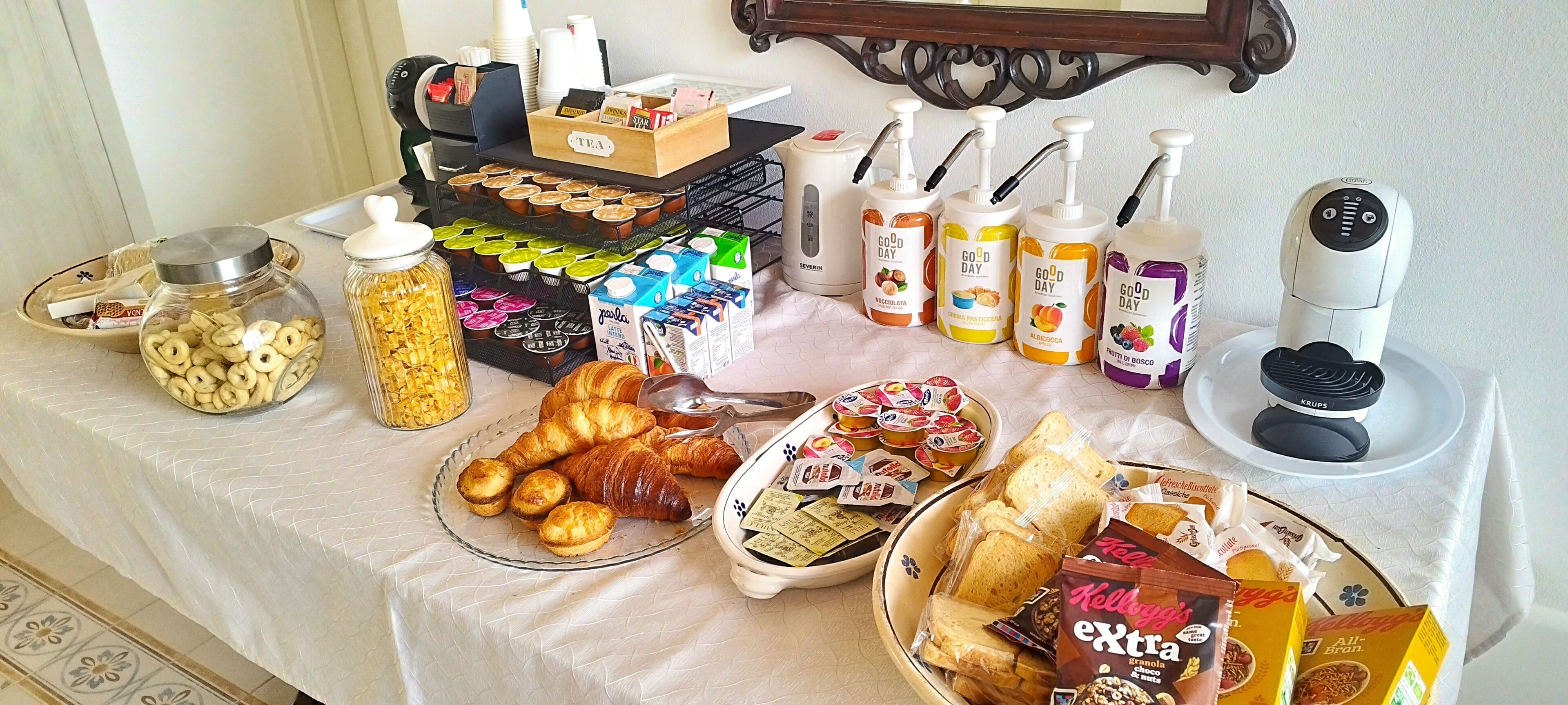 Una mesa de buffet con diversos alimentos, como pasteles, pan y bebidas.