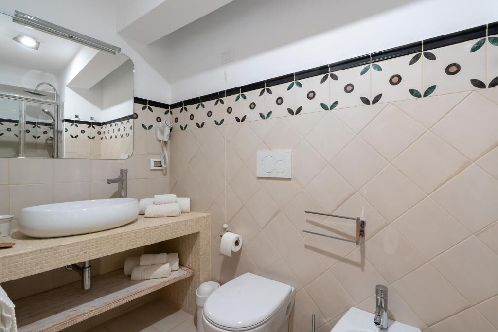 A bathroom with a white sink, a toilet, a mirror, and a towel rack.