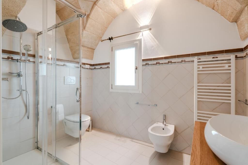 Een badkamer met een douche met glazen wand, een toilet, een bidet en een wastafel.