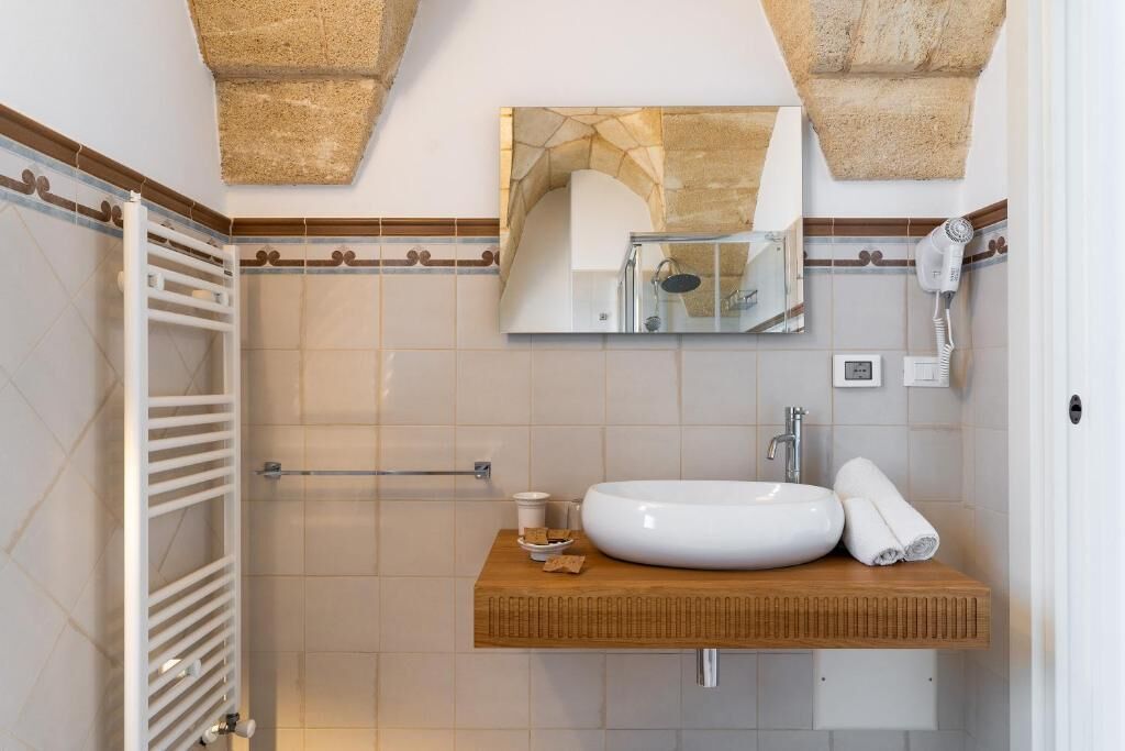 Un baño con lavamanos blanco, un espejo, toallero y ducha.