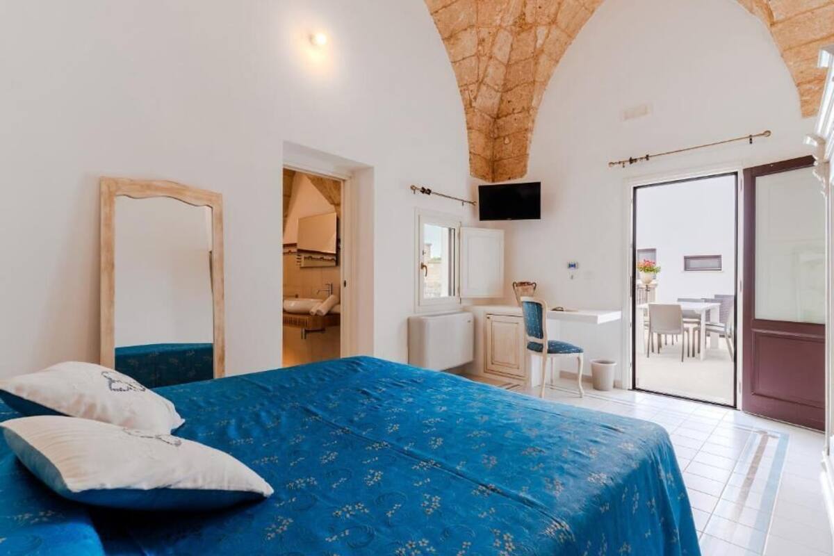 Ein Schlafzimmer mit Bett, Spiegel, Fernseher und Blick ins Freie.