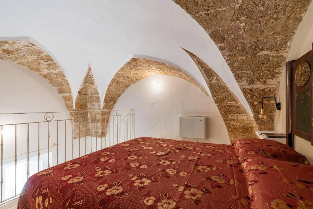 Ein Zimmer mit einem Bett, einem Fenster und einer Steindecke.