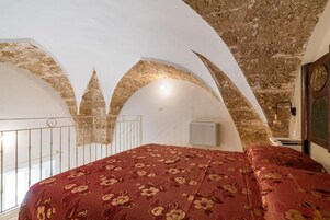 Una habitación con cama, ventana y techo de piedra.