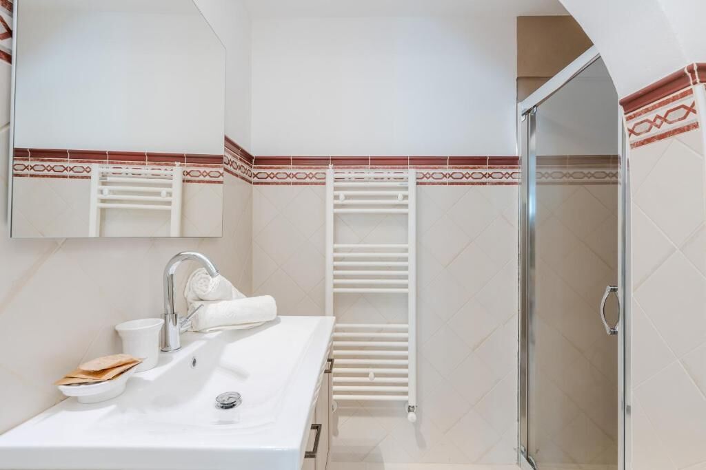 A modern bathroom with a sink, mirror, towel rack, and shower.