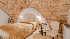 Ein Schlafzimmer mit Steinsandsteinwand, einem Bett, einem Sessel und einem kleinen Tisch.