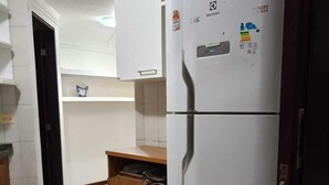 Eine Küche mit weißen Schränken, einem weißen Kühlschrank und einem Holzschrank.