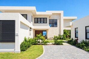 A modern two-story residential building with a paved driveway and a well-maintained lawn. - Beachfront 5BR Pool Villa | Private Chef, Butler | About Time Villa by Bocobay (St. Ann’s Bay)