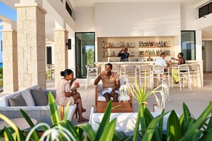 Et udendørs opholdsområde med bar, stensøjler og havudsigt.