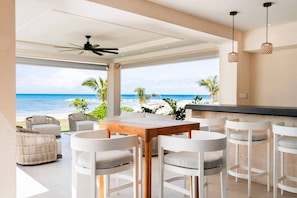 Un espace de restauration extérieur moderne offrant une vue sur la plage et l’océan.