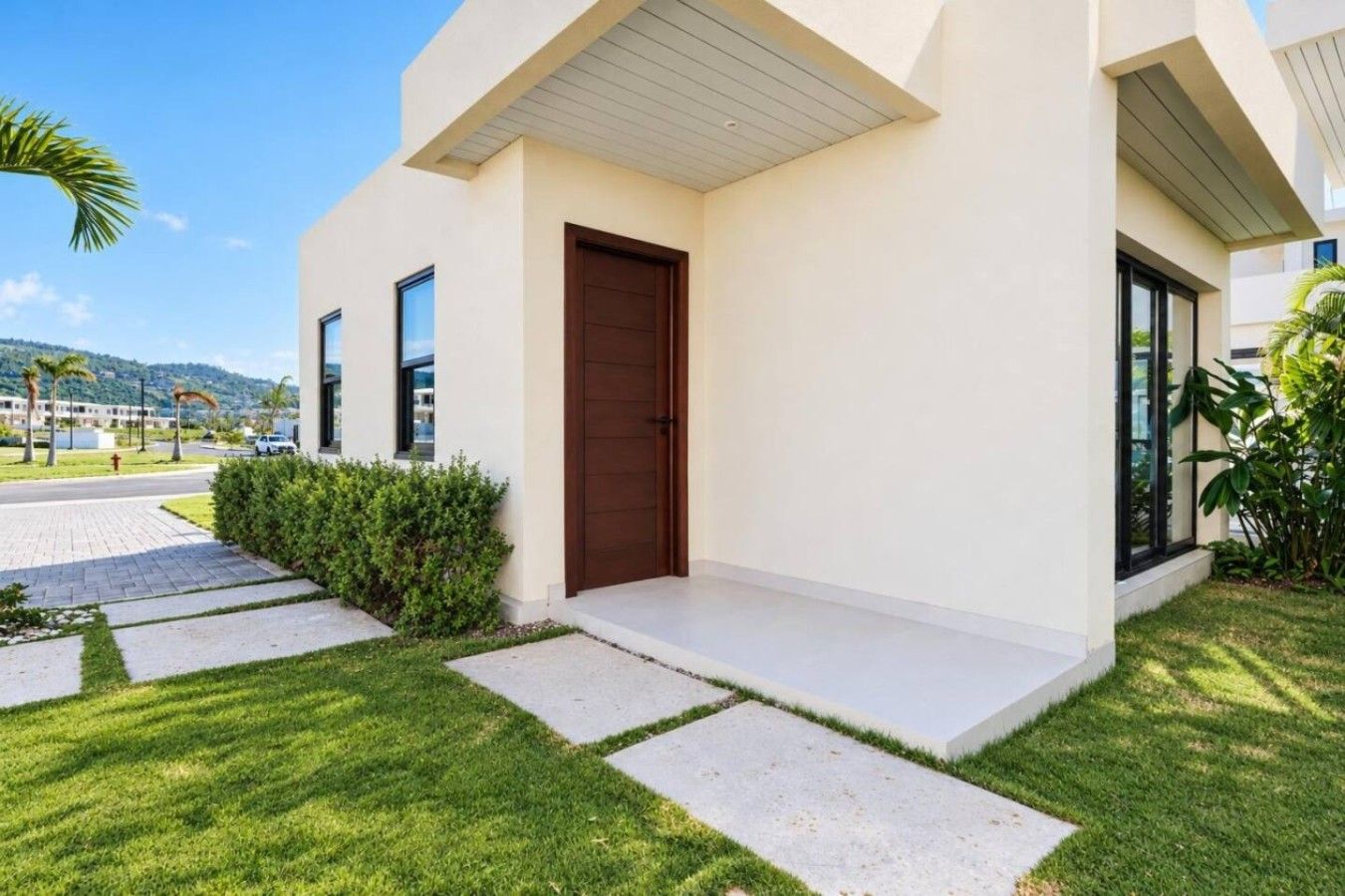Une maison moderne avec une porte d’entrée, une allée pavée et une pelouse bien entretenue.