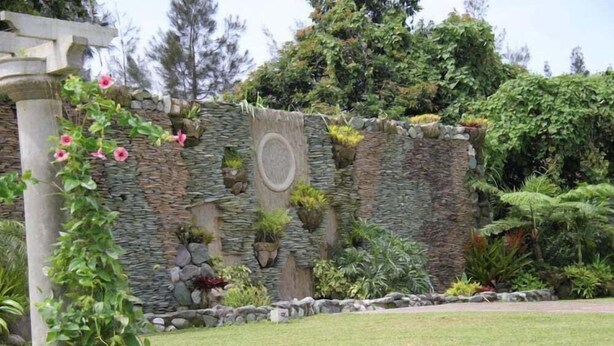 A garden with a stone wall, various plants, and a pergola. - The Q Hotel Restaurant (Tagaytay)