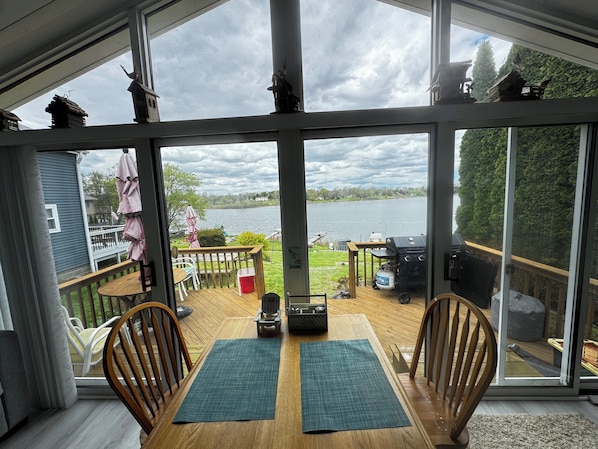 Eine Terrasse mit Tisch und Stühlen mit Blick auf einen See und einen Steg.
