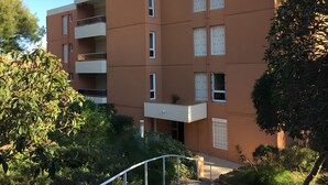 En flervåningsbostadsbyggnad med balkonger, ett platt tak och en trädgårdsyta.