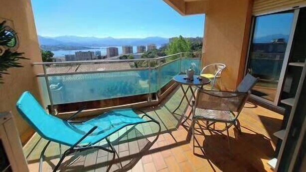 A balcony with a glass barrier, a pool, and a table with chairs. - Apartment with terrace and parking in Ajaccio (Ajaccio)