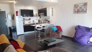 A modern living room with a sofa, a coffee table, and a purple bean bag. - Apartment with terrace and parking in Ajaccio (Ajaccio)