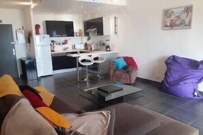 A modern living room with a sofa, a coffee table, and a purple bean bag. - Apartment with terrace and parking in Ajaccio (Ajaccio)