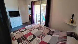 A bedroom with a bed, a TV, a wardrobe, and a balcony. - Apartment with terrace and parking in Ajaccio (Ajaccio)