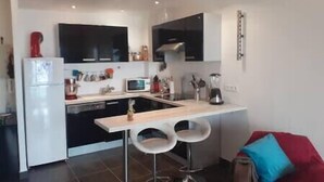 A compact kitchen with a refrigerator, microwave, and a small dining area with stools. - Apartment with terrace and parking in Ajaccio (Ajaccio)