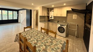 Une cuisine compacte équipée d’un lave-linge, d’une table à manger avec des chaises et offrant une vue sur l’extérieur grâce à une fenêtre.