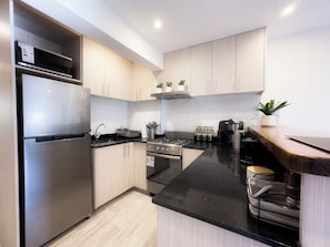 Una cucina moderna con elettrodomestici in acciaio inossidabile, mobili in legno e un piano di lavoro nero.