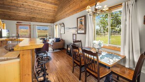Un interior de madera con comedor, chimenea y vistas al exterior.