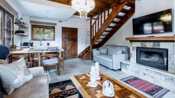 A spacious living area with a fireplace, a staircase, and a dining area. - MZ Reindeer (Distomo-Arachova-Antikyra)